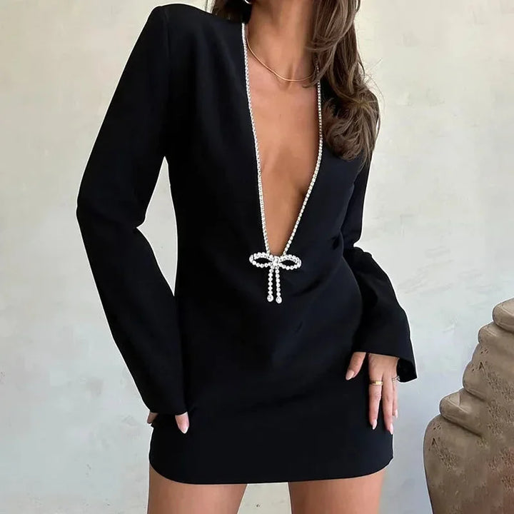 Robe courte chic avec décolleté plongeant, manches longues et détails perlés, en tissu doux pour une soirée élégante.