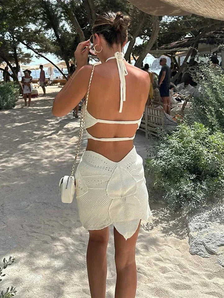 Robe courte en crochet, décolleté licou et découpes, idéale pour l'été à la plage, confectionnée dans un tissu léger et aéré.