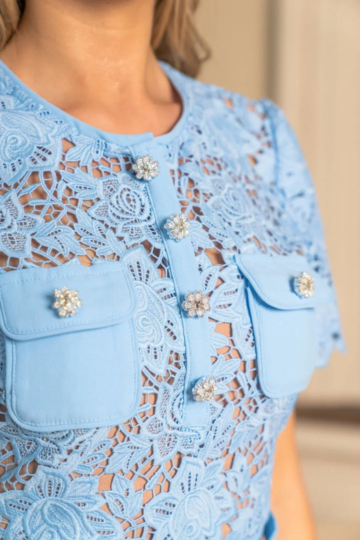 Robe mini femme bleue en dentelle avec manches courtes et détail floral sur le tissu, idéale pour les sorties estivales.