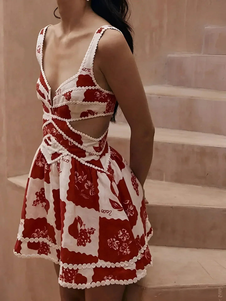 Robe courte florale rouge en coton, avec pompons blancs, idéale pour les journées d'été à la plage.