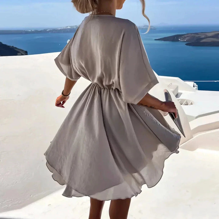 Robe courte fluide en tissu léger avec col V, cache-cœur et manches courtes, idéale pour une journée à la plage.