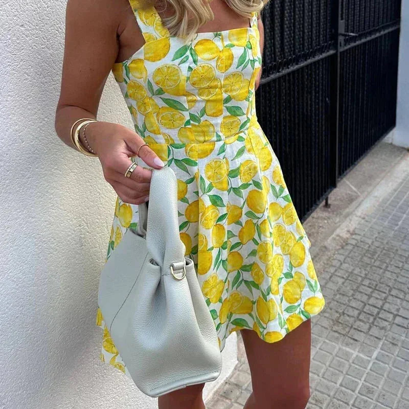 Robe courte jaune à motif citron, sans manches, en coton léger, avec encolure carrée et lien décoratif pour l'été.