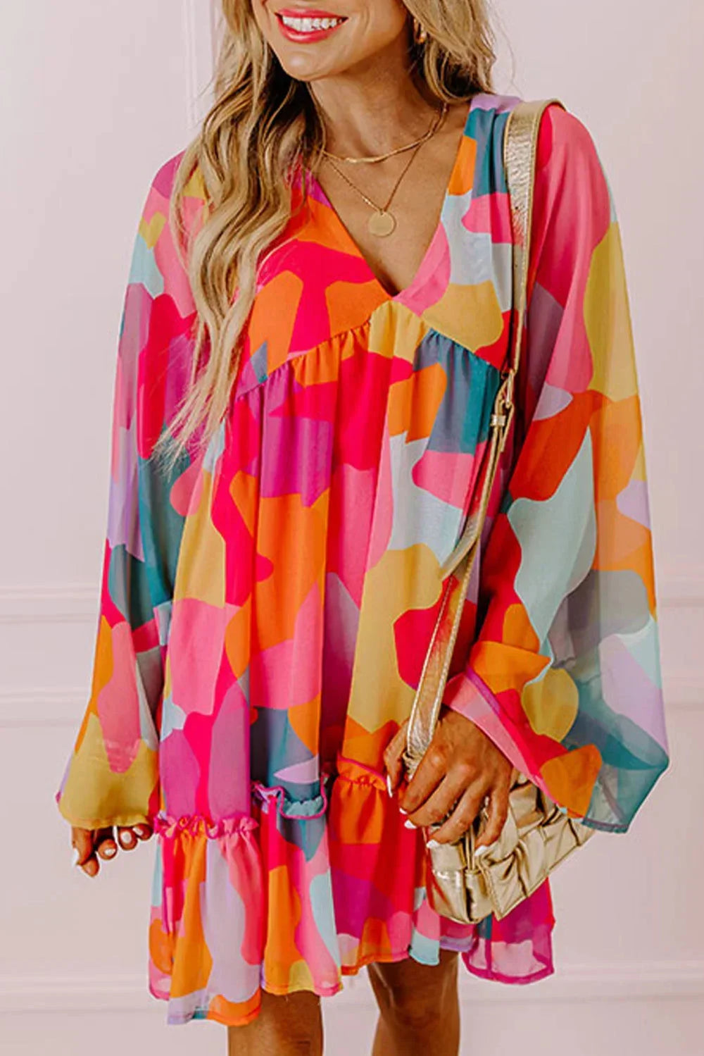 Robe courte décolletée en V, au tissu léger et coloré, avec des manches longues, idéale pour une journée à la plage.