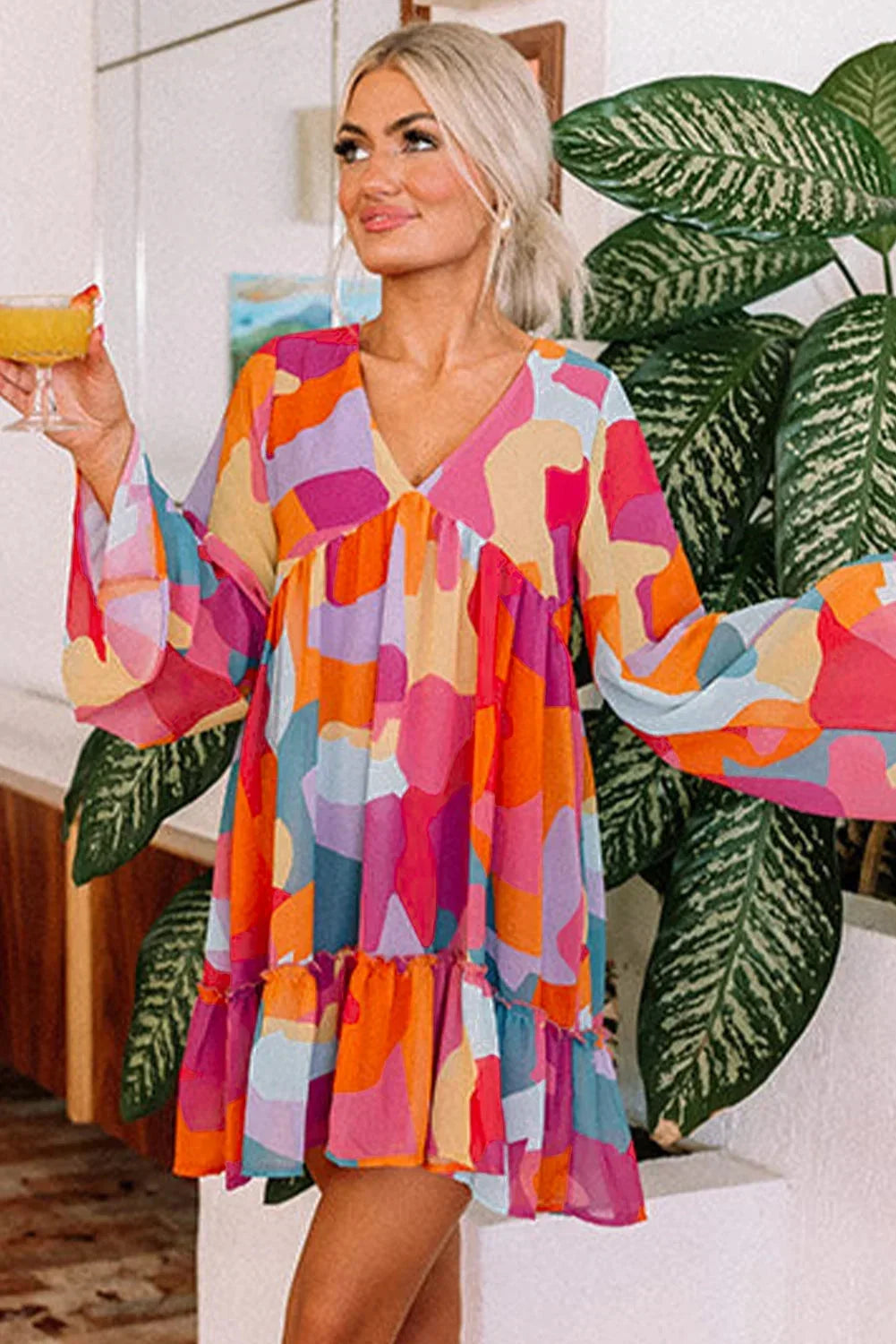Robe courte à motifs colorés, décolletée en V, manches longues, en tissu léger idéal pour les journées d'été à la plage.