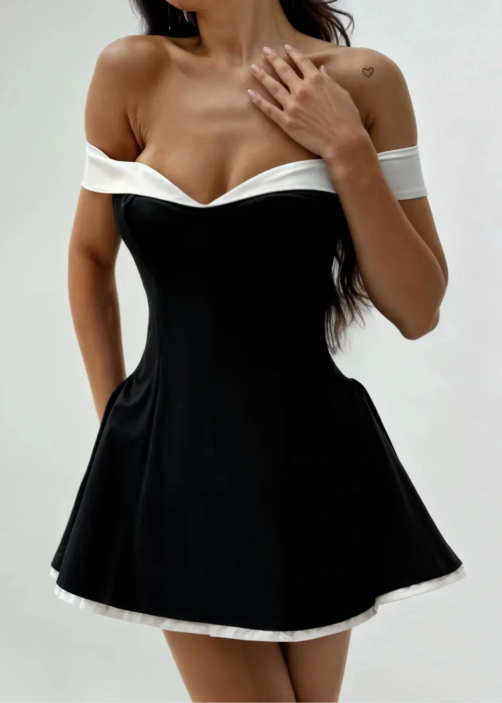 Robe courte noire à épaules dénudées, avec bord blanc et jupe évasée en tissu léger, idéale pour les soirées estivales.