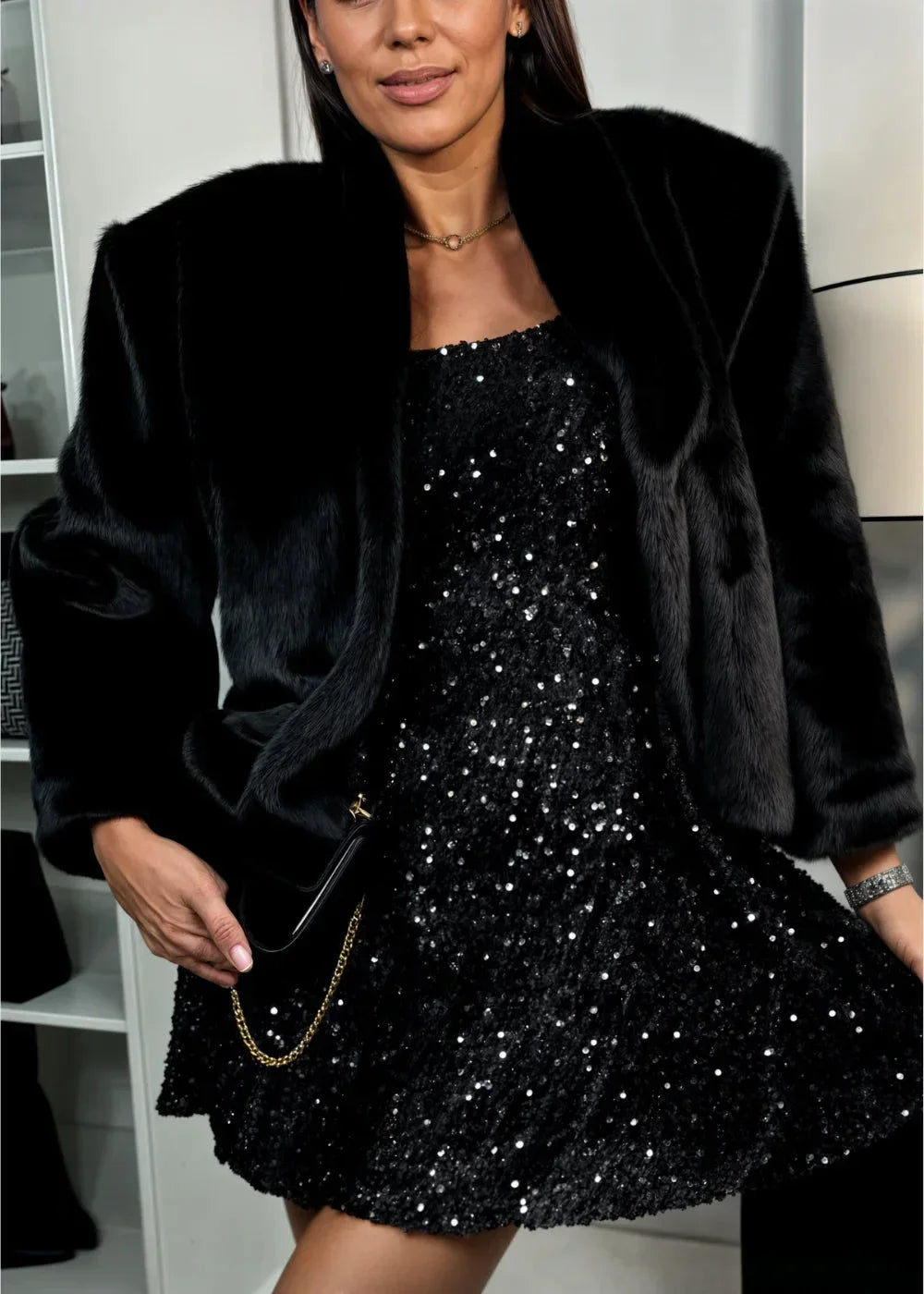 Robe courte noire en paillettes, manches longues, col en cœur, coupe ajustée pour soirées festives. Matière scintillante.