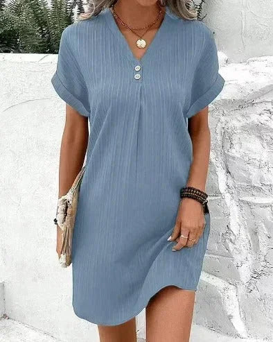 Robe courte plissée avec encolure en V, manches courtes, en tissu léger parfait pour l'été. Détails de boutons à l'avant.
