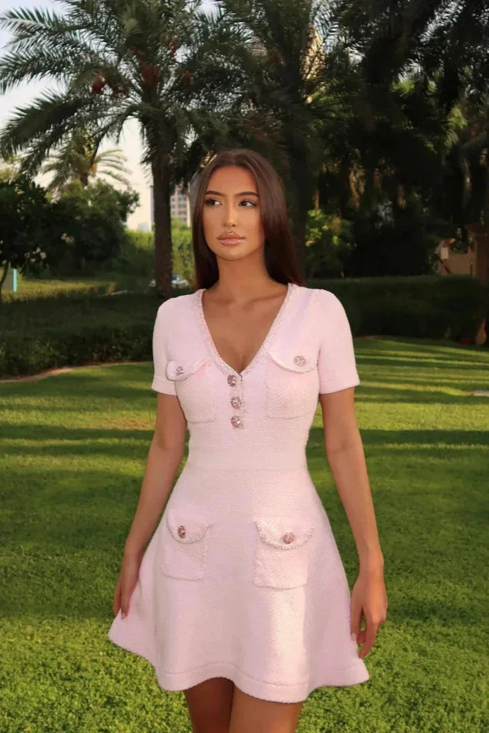 Robe courte rose en coton léger, boutons décoratifs, poches sur les côtés et manches courtes avec col V pour un style estival.