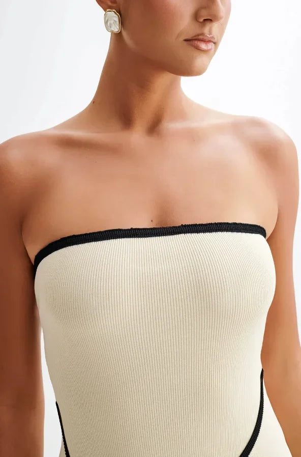 Robe courte sans manches beige, bordures noires, nœud à la taille, silhouette ajustée, tissu léger pour une soirée élégante.