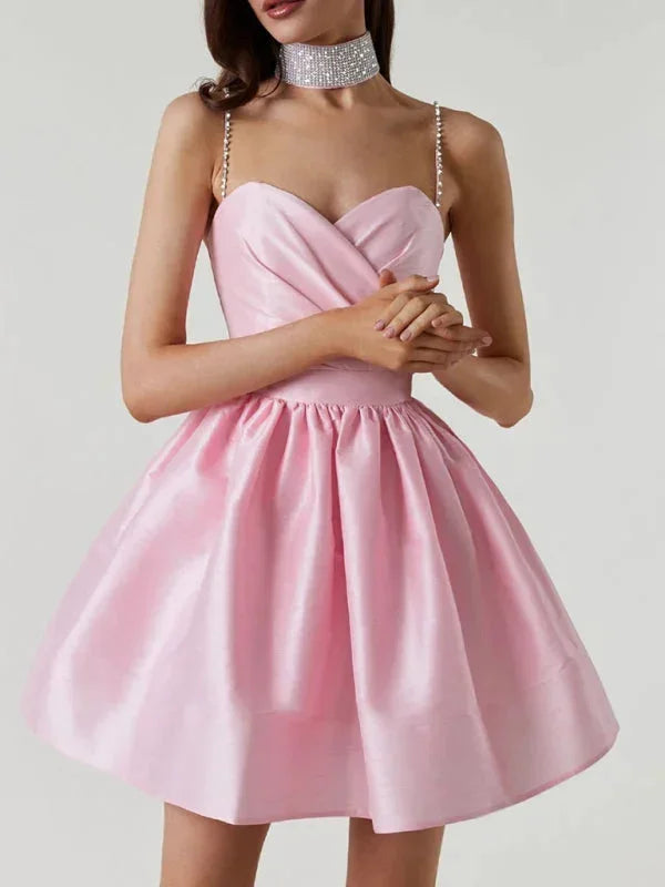 Robe courte satinée avec bretelles strass, col cœur et dos nu, parfaite pour les soirées. Disponible en plusieurs couleurs.