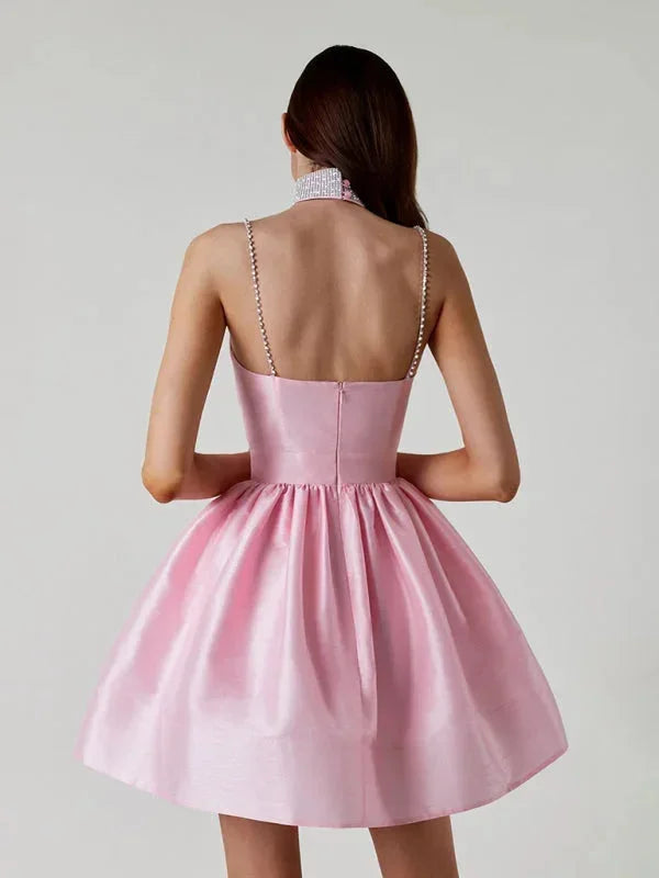 Robe courte satinée avec bretelles strass, col en cœur et dos nu, disponible en plusieurs couleurs. Idéale pour les soirées.