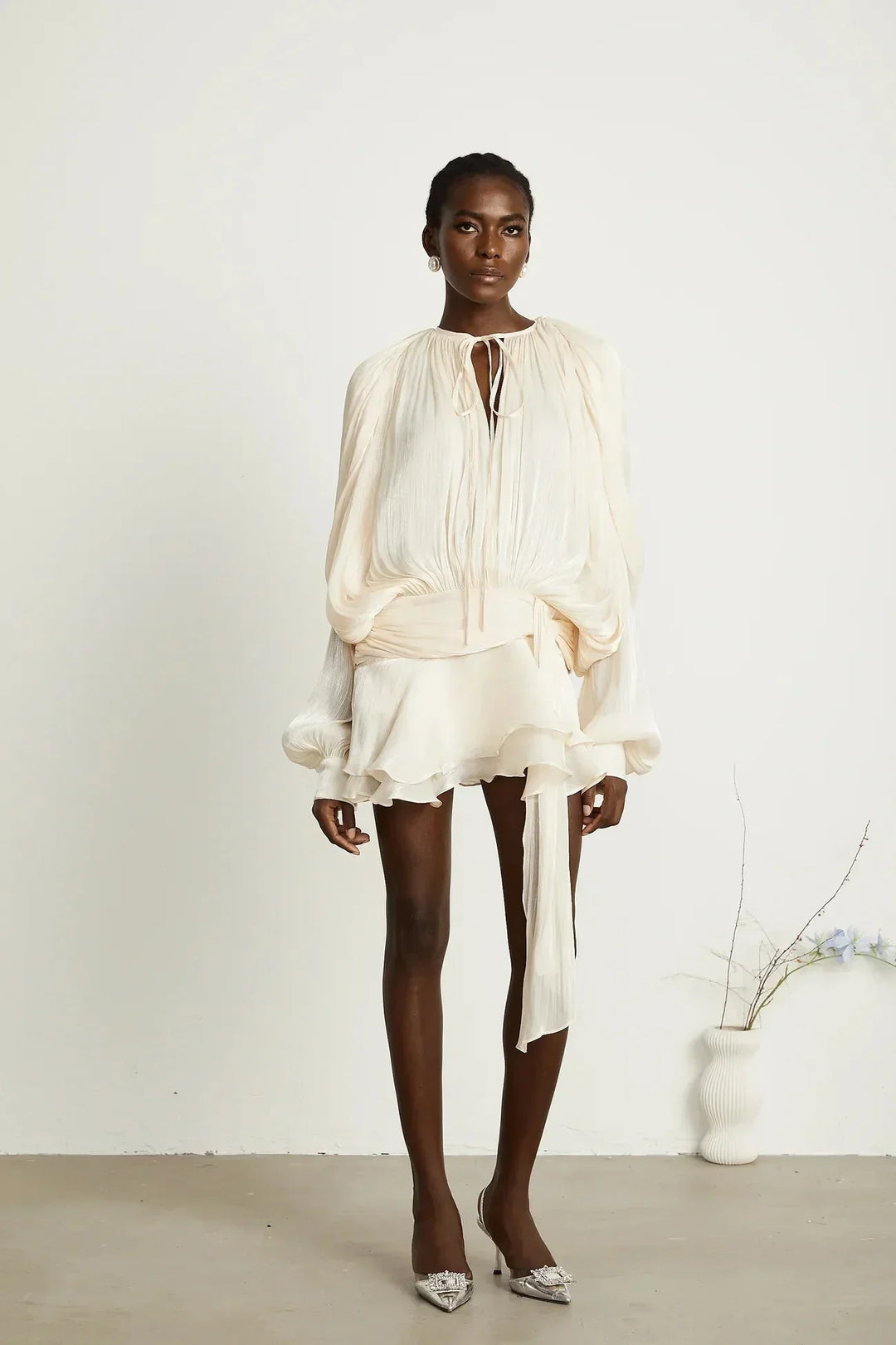 "Robe courte satinée fluide avec nœuds aux manches longues, disponible en plusieurs couleurs, idéale pour les soirées."