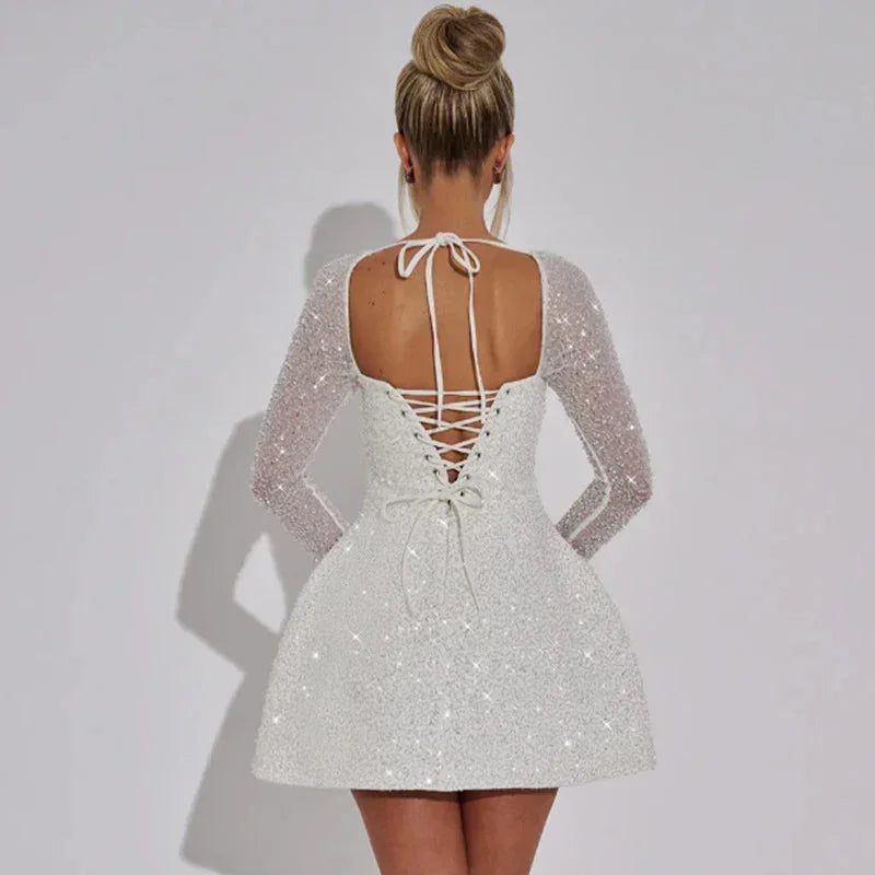 Robe courte scintillante avec manches longues transparentes, bustier carré, idéale pour soirées, en tissu léger et brillant.