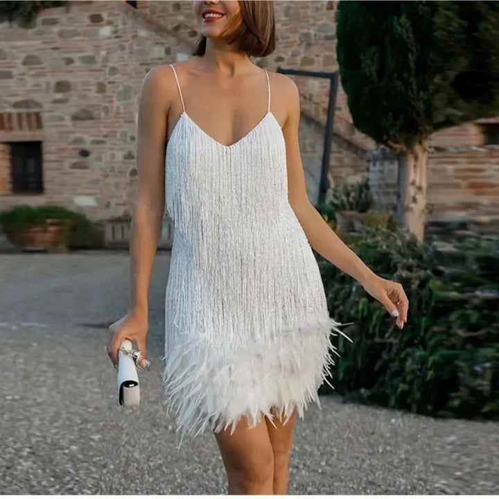 Robe courte en sequins argentés avec plumes, bretelles fines et coupe élégante, idéale pour une soirée cocktail.