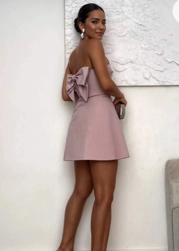 Robe courte rose poudré sans bretelles, coupe ajustée, en tissu léger, avec pochette assortie pour les soirées.