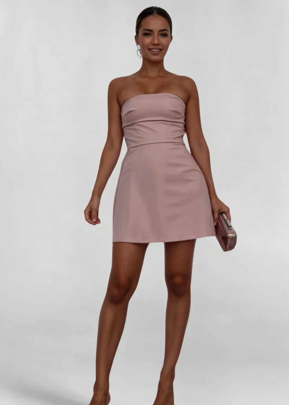 Robe courte strapless rose poudré en tissu doux, coupe ajustée, accompagnée d'une pochette assortie pour soirée élégante.