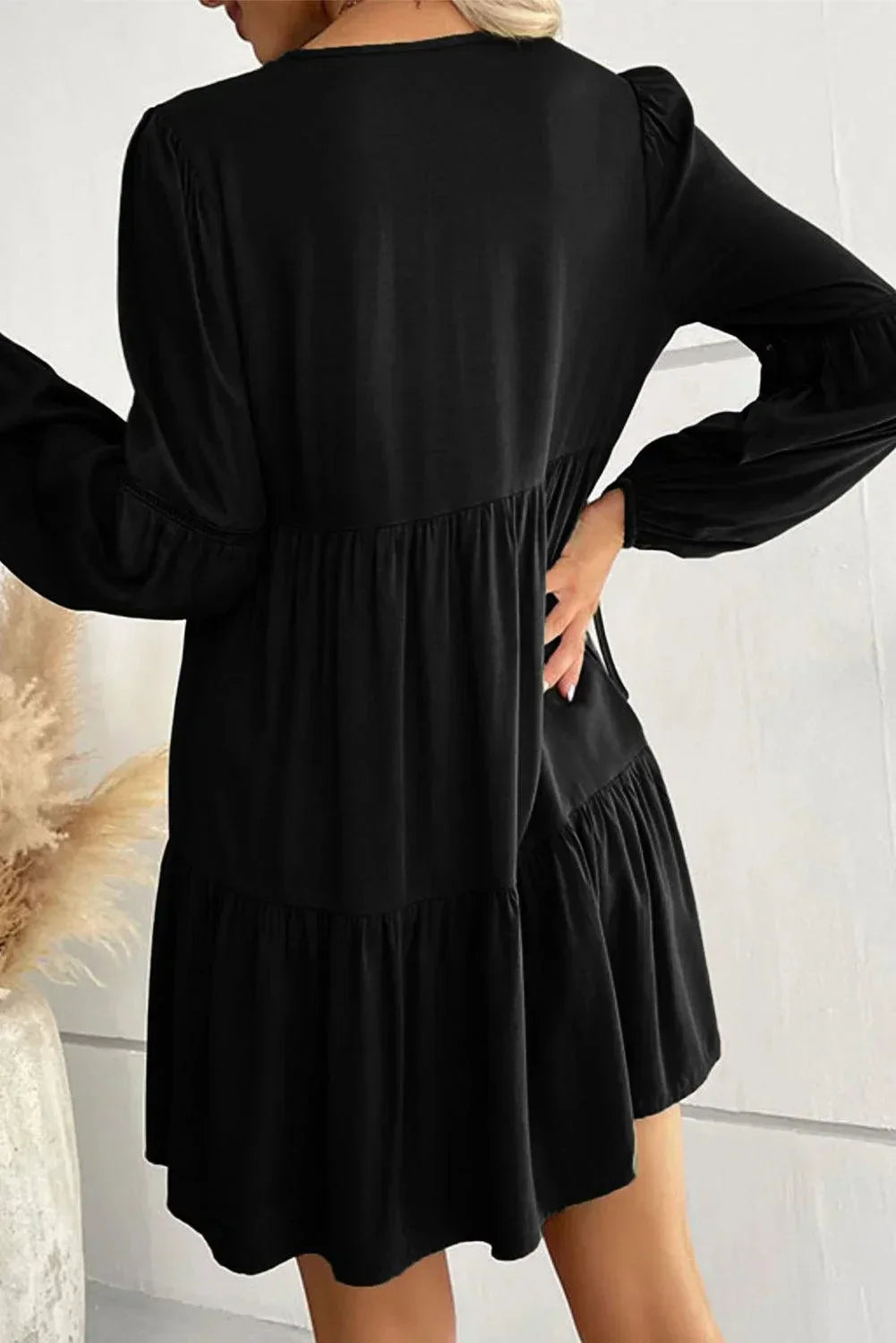 Robe courte volantée à lacets, manches longues, en tissu doux, idéale pour l'automne avec son design élégant et féminin.