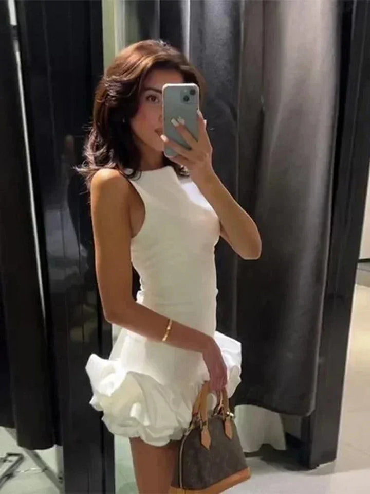 Robe courte volantée sans manches en coton léger, avec un design fluide et disponible en plusieurs couleurs vives.