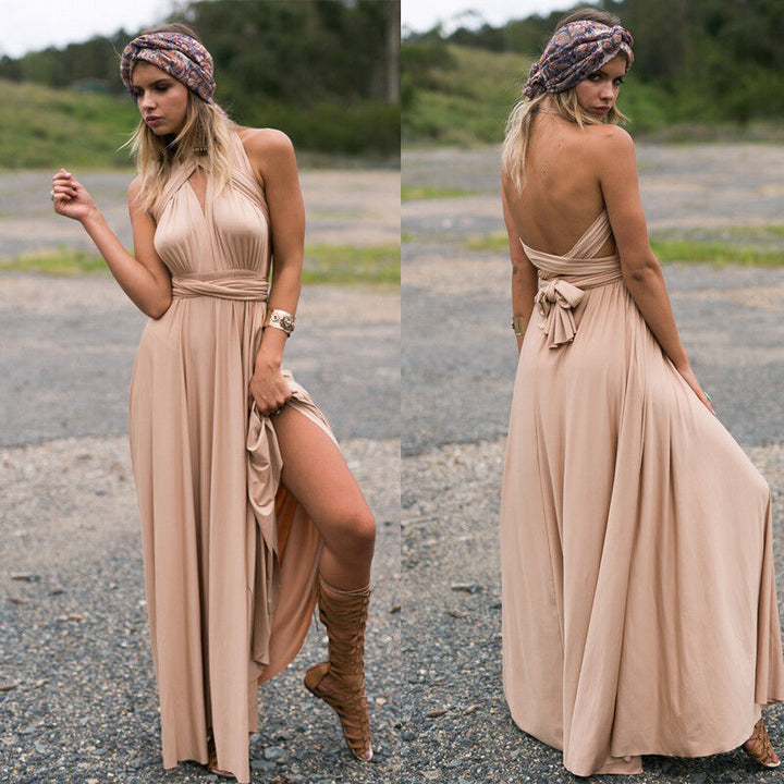 Donna con abito lungo beige senza spalline, sandali alti marroni e fascia colorata, in posa all'aperto. Moda estiva elegante e boho chic.