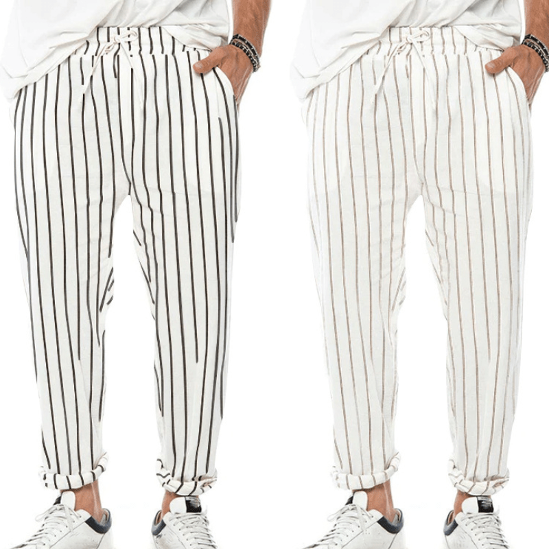 Pantaloni uomo a righe verticali bianche e nere, stile casual, con coulisse in vita, abbinati a scarpe sportive bianche.