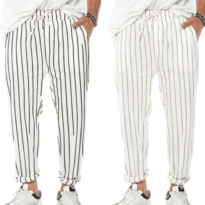Pantaloni uomo a righe verticali bianche e nere, stile casual, con coulisse in vita, abbinati a scarpe sportive bianche.