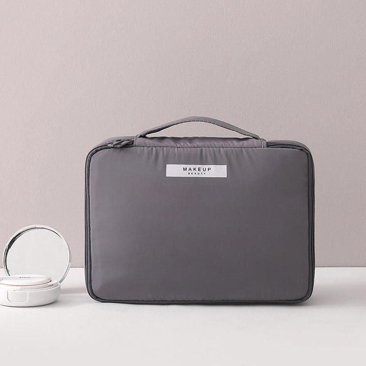 Borsa trucco grigia con manico, design elegante e compatto, ideale per organizzare cosmetici. Perfetta per viaggi e uso quotidiano.
