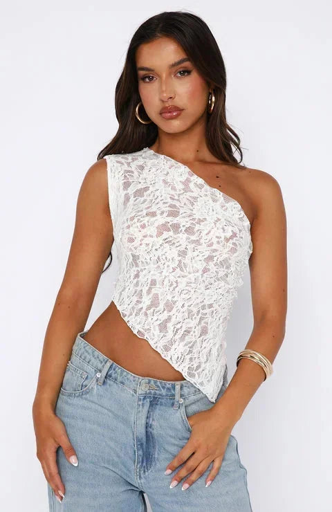 Top femme asymétrique en dentelle blanche, avec une texture délicate et des détails raffinés, idéal pour un look élégant.