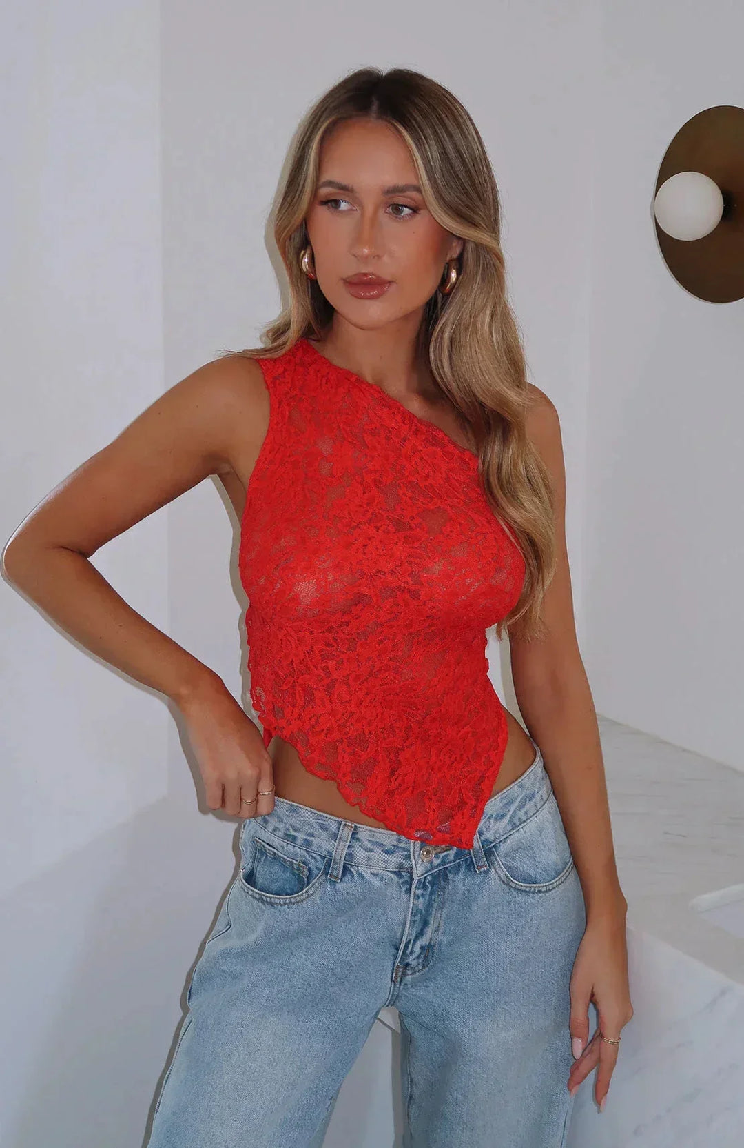 Top rouge asymétrique en dentelle avec texture délicate, manches courtes et détail de découpe sur le dos.