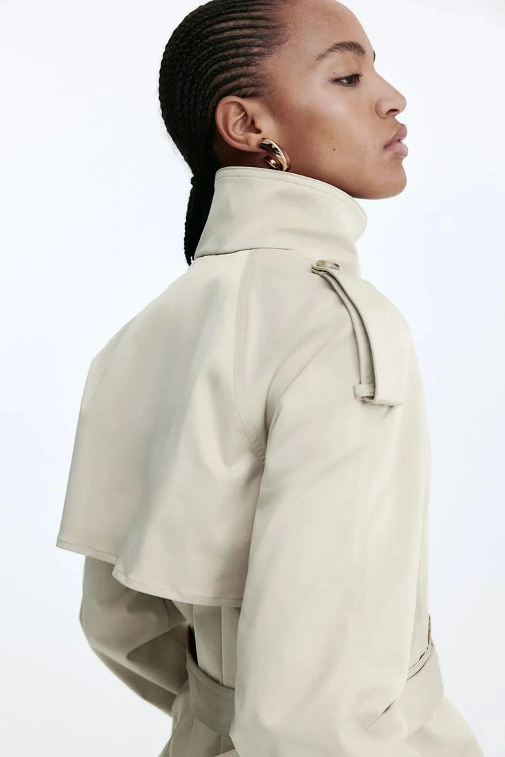 Trench-coat femme noir avec col montant et ceinture nouée, en matériau léger et résistant aux intempéries.