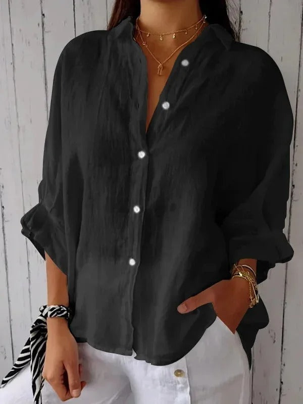 Camicia nera da donna in lino, maniche lunghe, bottoni bianchi, stile casual elegante, abbinata a pantaloni bianchi.