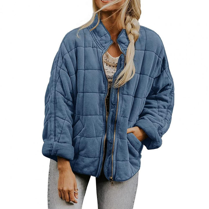 Giacca trapuntata blu donna, stile casual, con zip frontale e tasche, indossata su maglia chiara e jeans. Moda autunnale, abbigliamento femminile.