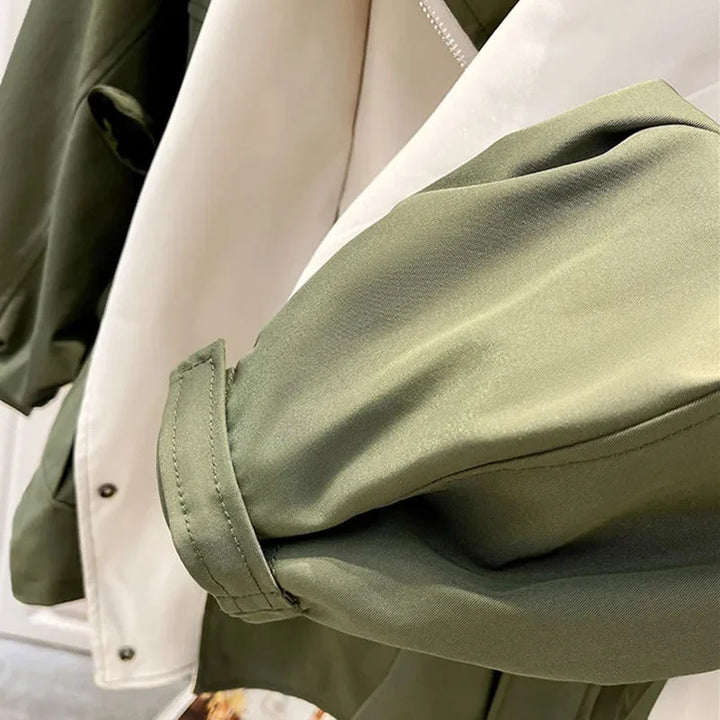 Veste coupe-vent femme verte, avec capuche amovible, en matériau léger et déperlant pour un usage polyvalent.