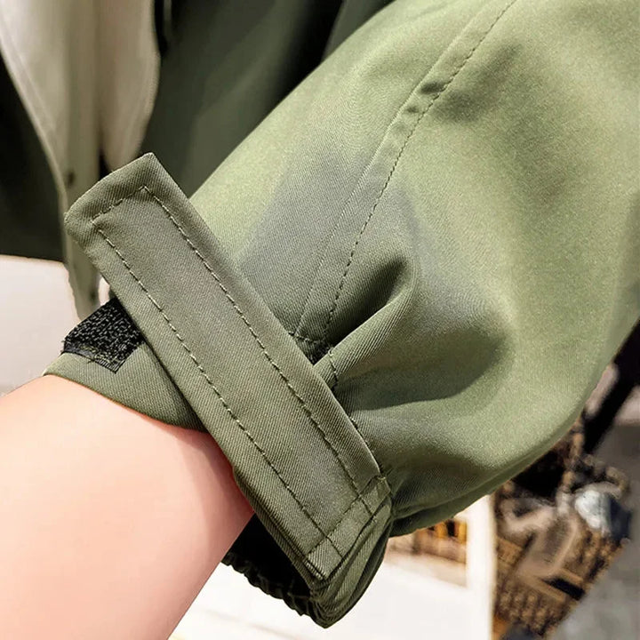 Veste coupe-vent femme verte, légère, avec capuche amovible, coupe sportive et poches pratiques.