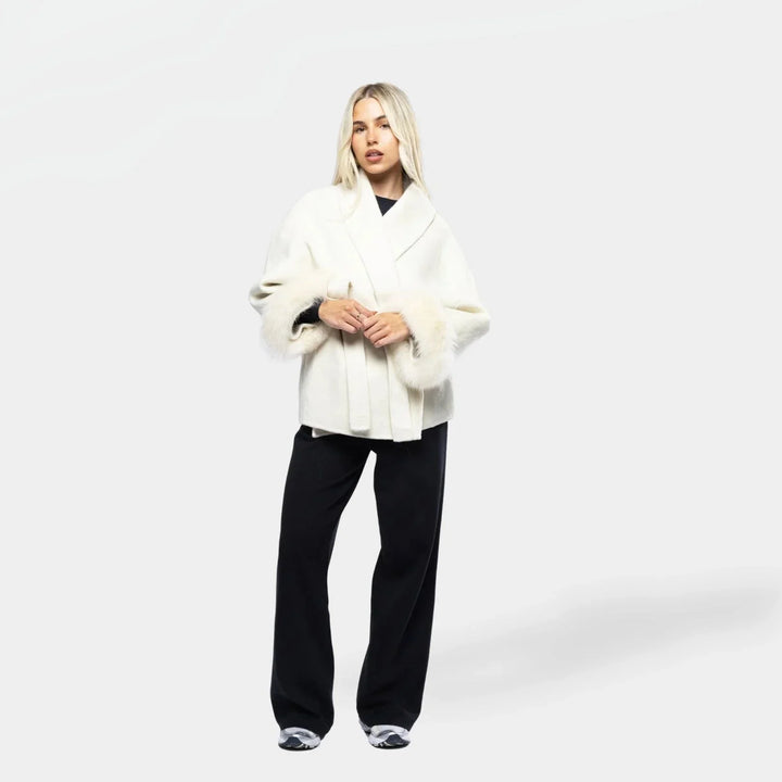 Veste femme blanche ceinturée avec manches en fourrure synthétique, parfaite pour les occasions élégantes.