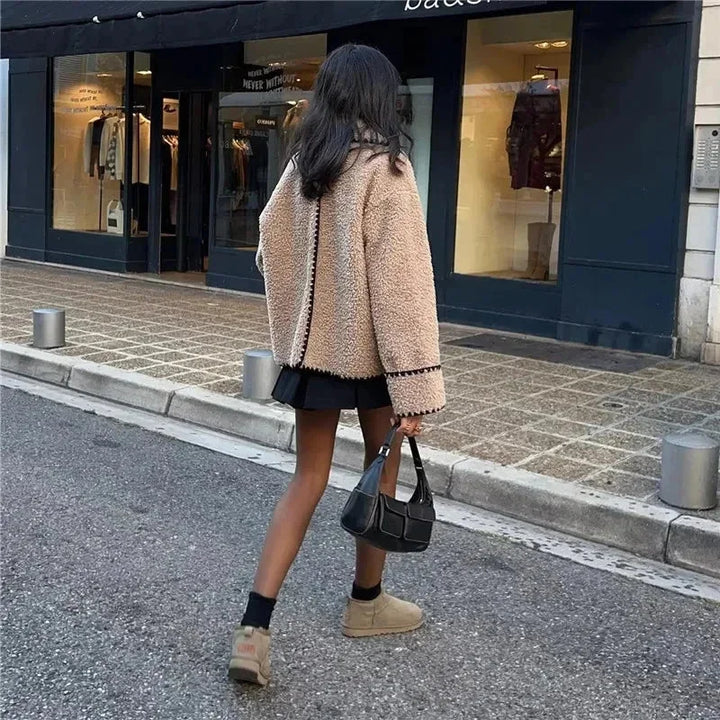 Veste teddy femme beige avec coutures noires, en matériau doux, coupe confortable.