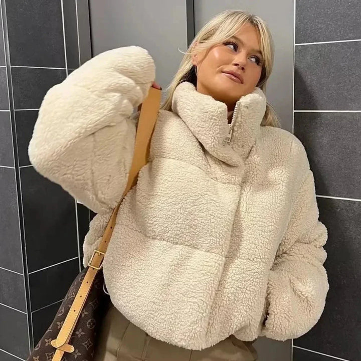 Veste teddy puffer beige femme à col montant, conçue en matériau doux pour le confort et la chaleur.